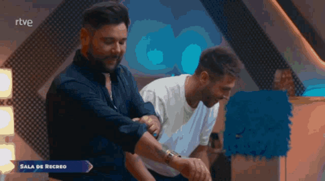 two men are standing next to each other with the words sala de recreo in the corner