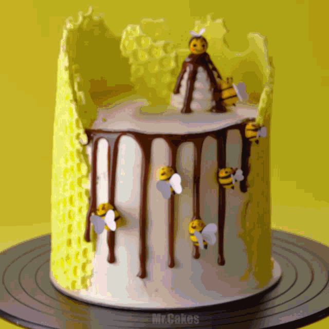 a yellow and white cake with bees and honeycomb decorations