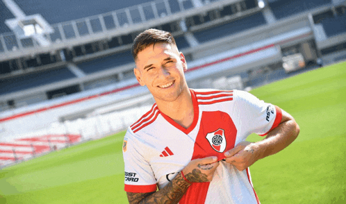 a man wearing a red white and blue adidas jersey smiles for the camera