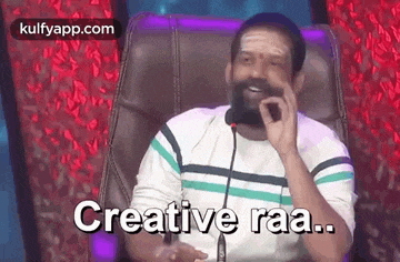 a man with a beard is sitting in a chair talking into a microphone and making a funny face .