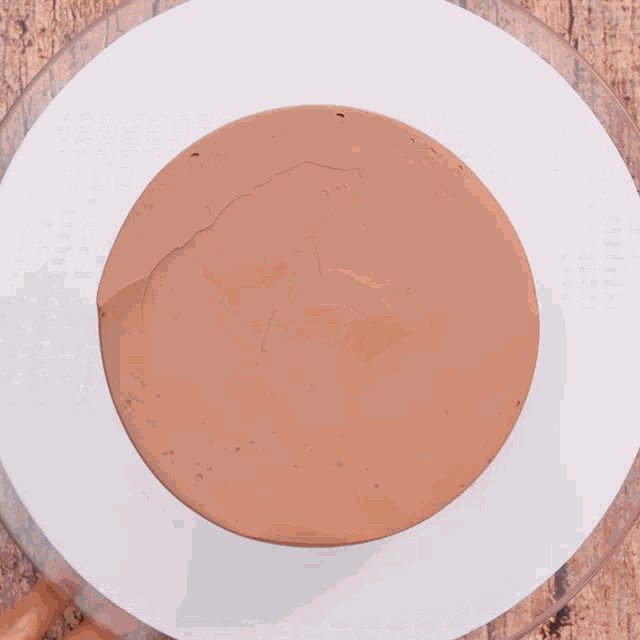 a chocolate cake is sitting on a cooling rack and chocolate is being poured on it