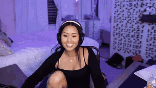 a woman wearing headphones is sitting on a chair in front of a bed .