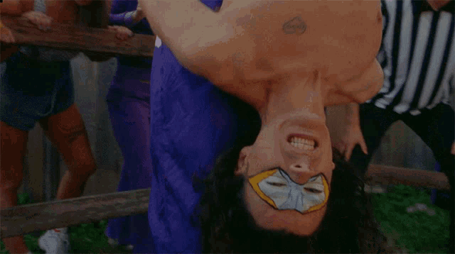 a man in a purple shirt is doing a handstand in front of a group of people