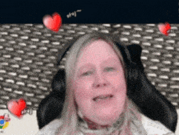 a woman wearing headphones is sitting in front of a screen with hearts floating around her