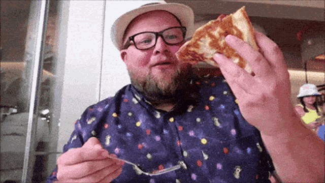 a man in a hat and glasses is eating a slice of pizza