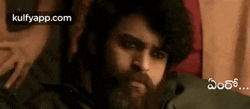 a man with a beard is sitting on a bed with a woman .
