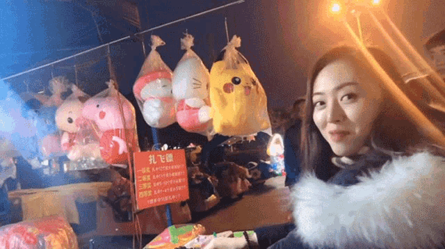 a woman stands in front of a display of stuffed animals and a sign that says ' balloons '