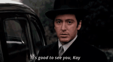 a man in a suit and hat is standing in front of a car and saying it 's good to see you , kay