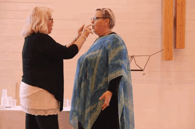 two women are standing next to each other and one is wearing a blue and green poncho