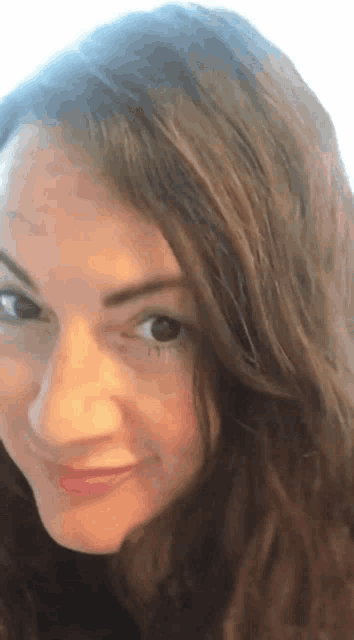 a close up of a woman 's face with long hair and a smile .