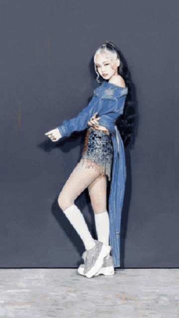 a woman in a blue denim jacket and white socks is standing on one leg