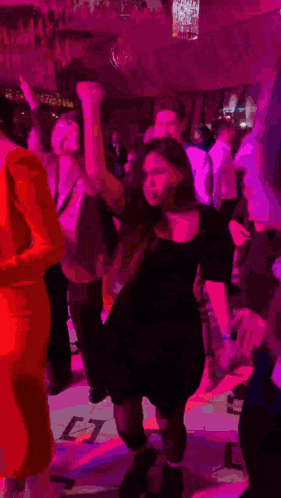 a group of people are dancing at a party in a dark room with purple lights .