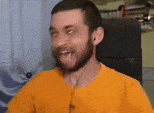 a man with a beard wearing an orange shirt is sitting in a chair