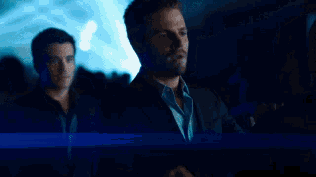 a man in a suit talks to a woman in a dark room