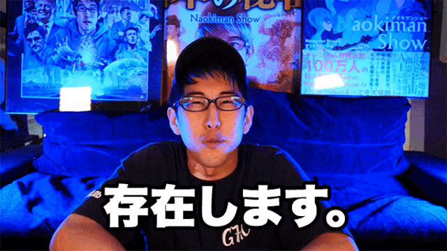 a man wearing glasses is sitting in front of a naokiman show poster
