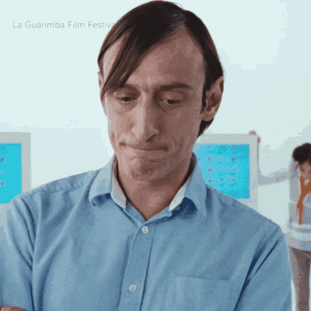 a man with a sad look on his face is standing in front of a la guarimba film festival poster