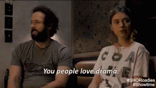 a man and a woman are sitting on a couch and the woman is wearing a shirt that says " you people love drama "