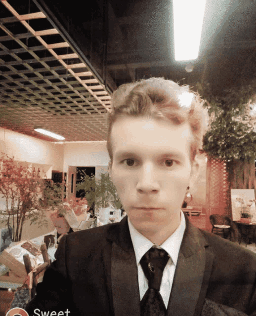 a man in a suit and tie stands in front of a sign that says sweet on it