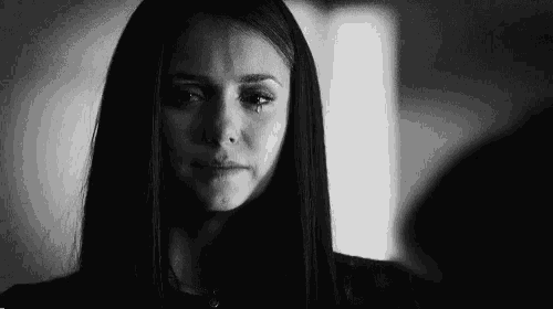 a black and white photo of a woman crying with a tear running down her face .