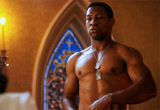 a shirtless man with a dog tag around his neck that says ' n.i.n. '
