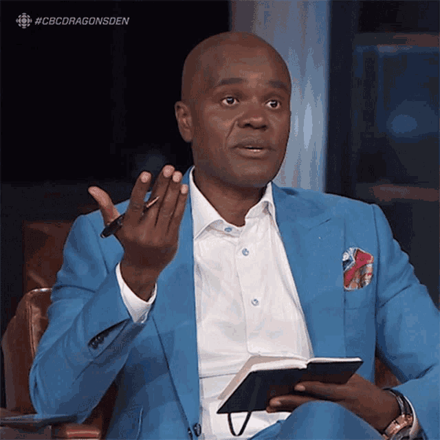 a man in a blue suit holds a notebook and a pen