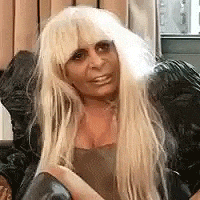 a woman with long blonde hair is sitting on a couch .
