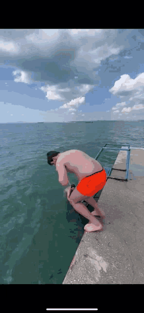 a man in orange shorts is jumping into the ocean