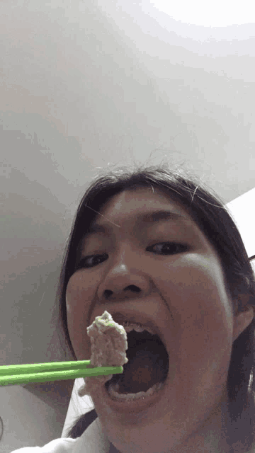 a woman with chopsticks in her mouth eating something