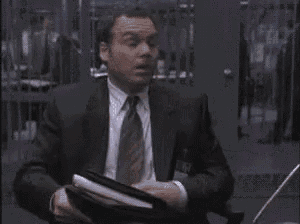a man in a suit and tie is standing in front of a computer .