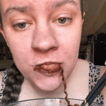 a woman eating a bowl of food with a spoon in her mouth