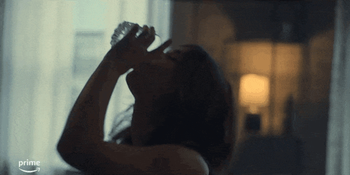 a woman is drinking water from a bottle and the word prime is on the bottom of the screen