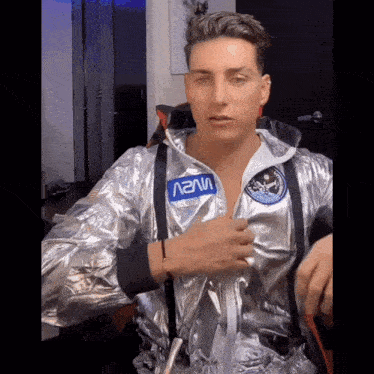 a man wearing a nasa jacket and suspenders adjusts his jacket