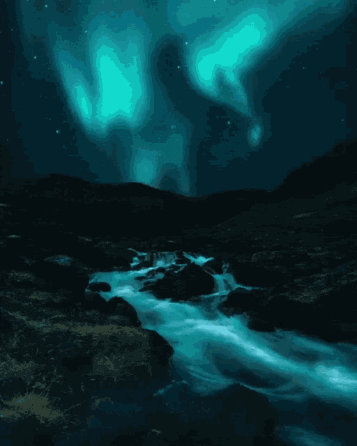 the aurora borealis shines over a river at night