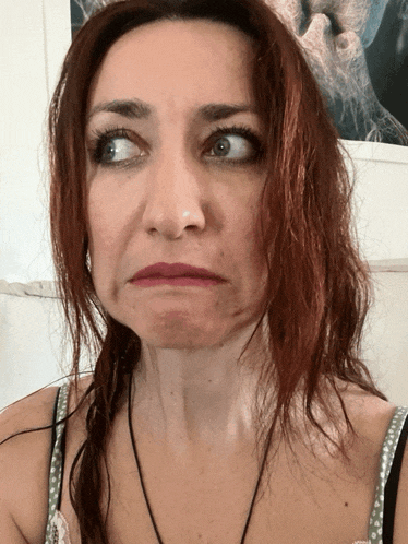 a woman with red hair makes a funny face in front of a picture