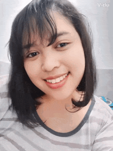 a woman with a striped shirt is smiling for the camera and the word vidu is on the bottom