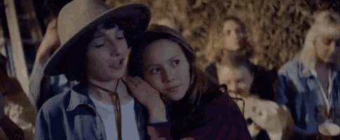 a boy and a girl are standing next to each other . the girl is wearing a cowboy hat .