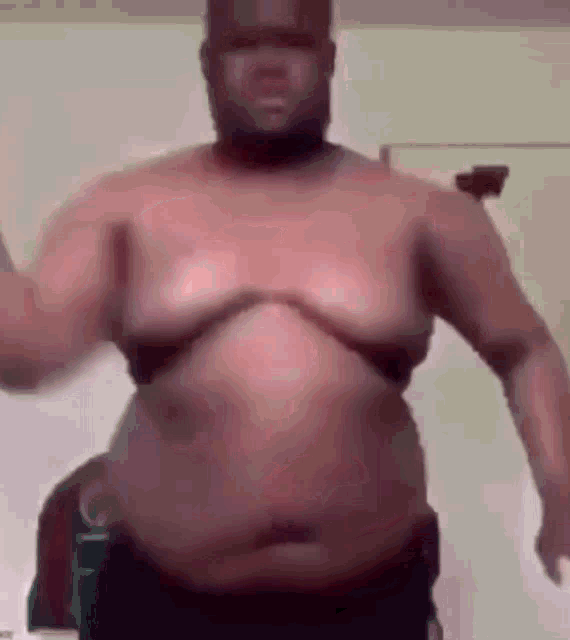 a man without a shirt is standing in a room with his arms outstretched .