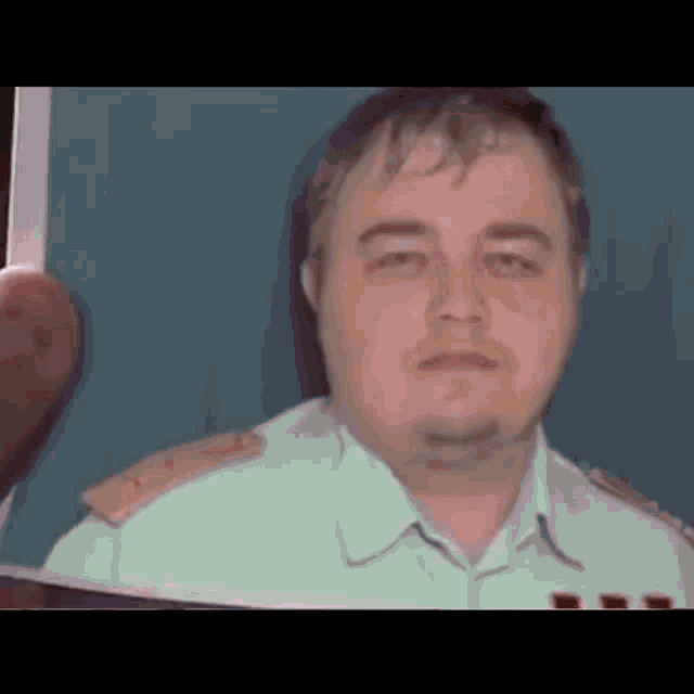 a man in a white shirt is holding a piece of paper in front of him .
