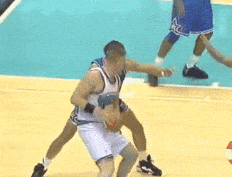 a basketball player wearing a white jersey with the word magic on it tries to block another player