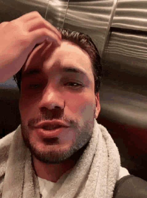 a man with a beard and a towel around his neck is touching his head