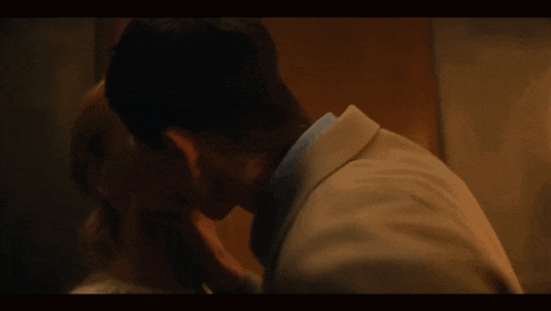 the back of a man in a tan suit is shown in a dark room .