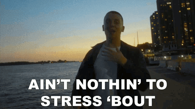 a man stands in front of a body of water with the words " ain 't nothin ' to stress bout "