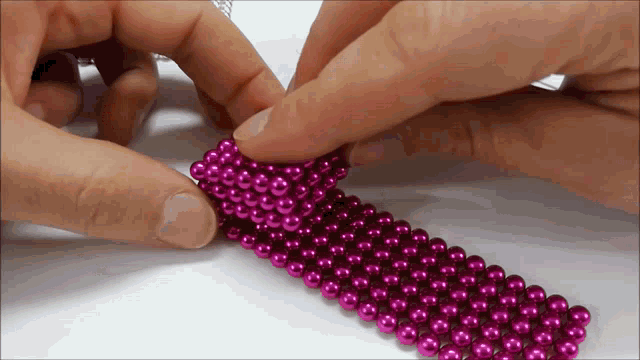 a person is holding a bunch of pink beads
