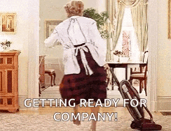 a woman is holding a vacuum cleaner in a living room and says `` getting ready for company ! ''
