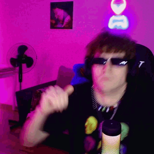 a man wearing sunglasses and headphones is giving a thumbs up in front of a microphone