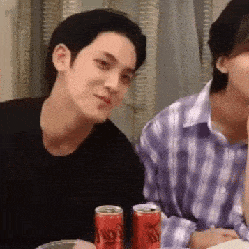 a man and a woman are sitting at a table with two cans of coca cola .