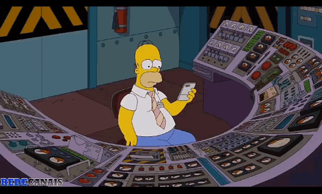 homer simpson is sitting at a control panel looking at his cell phone