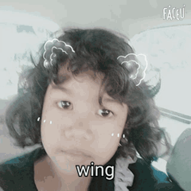 a young girl with curly hair has the word wing written on her forehead