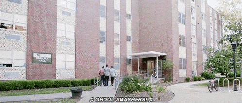 a group of people are walking in front of a brick apartment building .