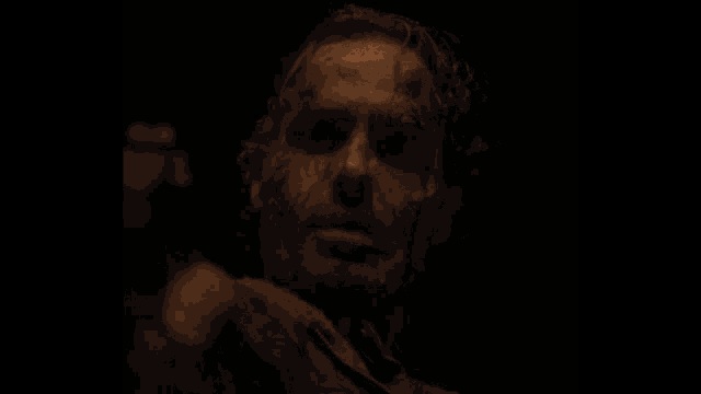 a close up of a man 's face with blood on it in the dark .